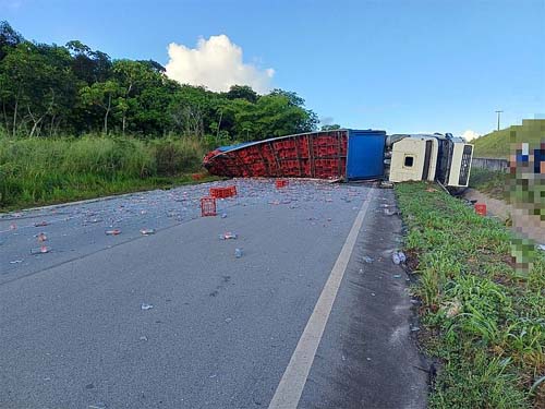 Carreta carregada de garrafas de vidro tomba e bloqueia rodovia, em São Miguel dos Campos