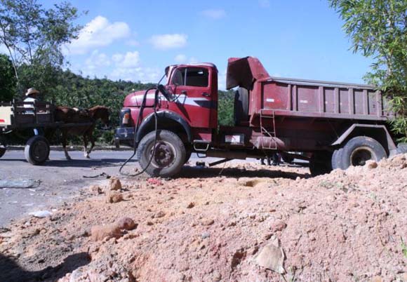 Caçamba carregada de areia perde o freio em ladeira, atinge barranco e capota